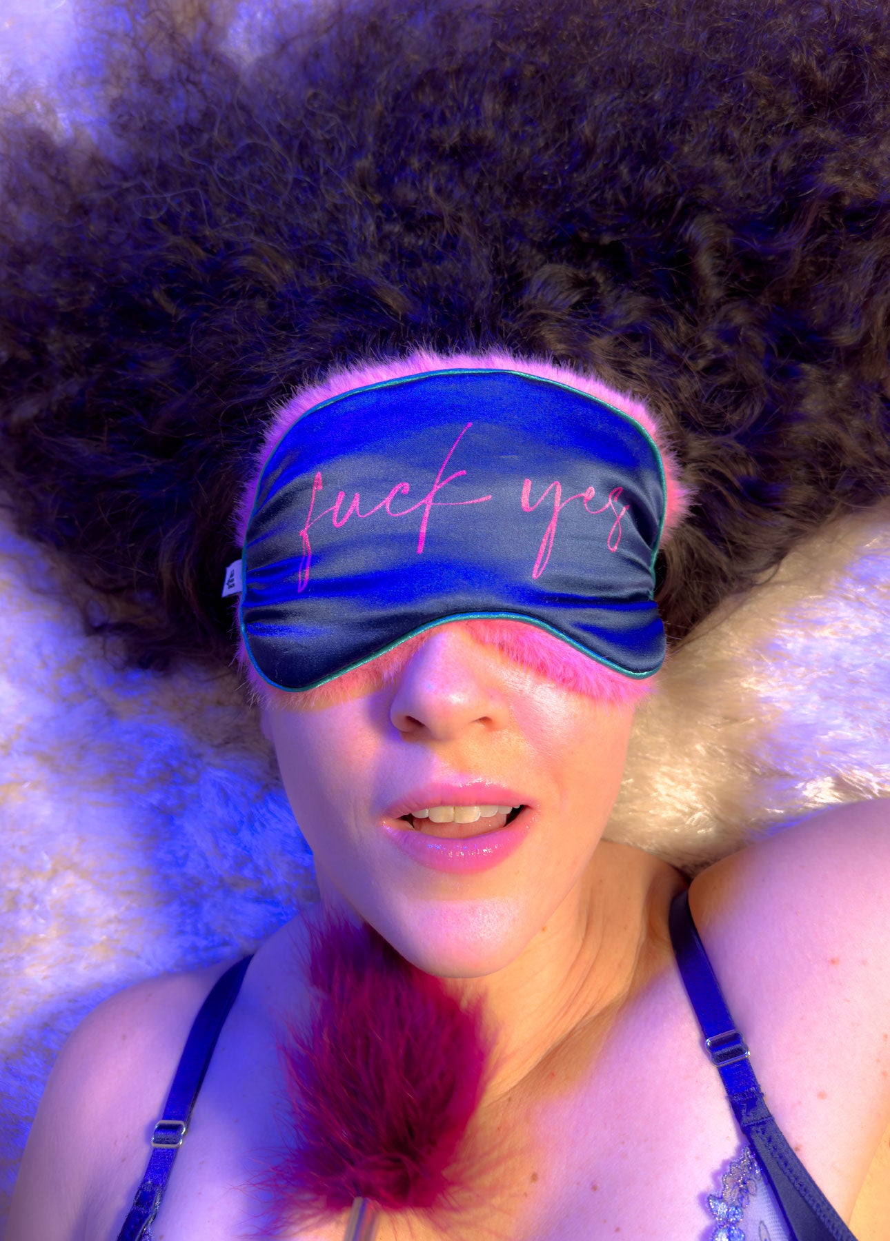  A woman wearing a blue and pink BDSM eye mask, showcasing a blend of elegance and allure in her expression